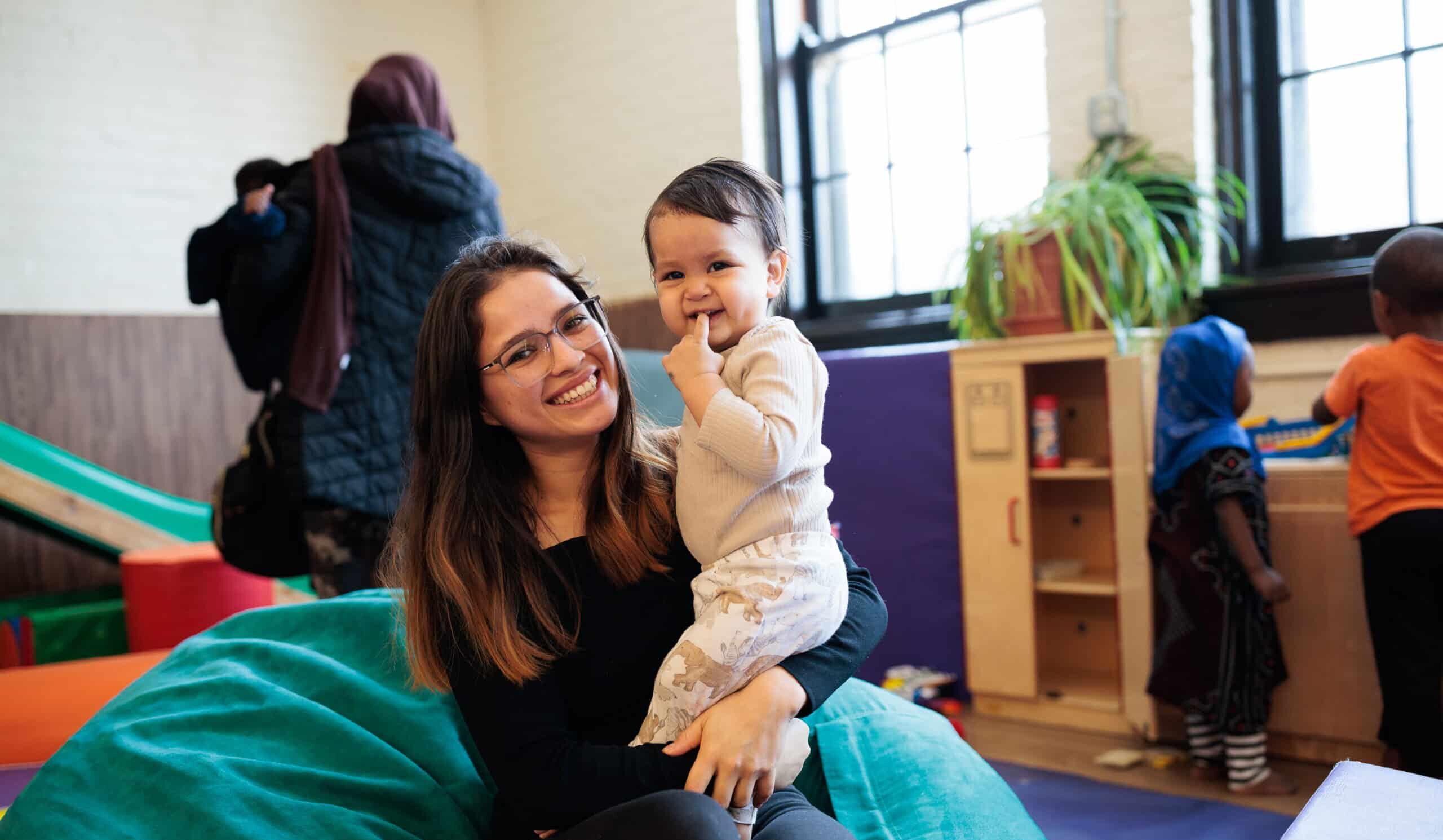 A smiling mom holds her young child