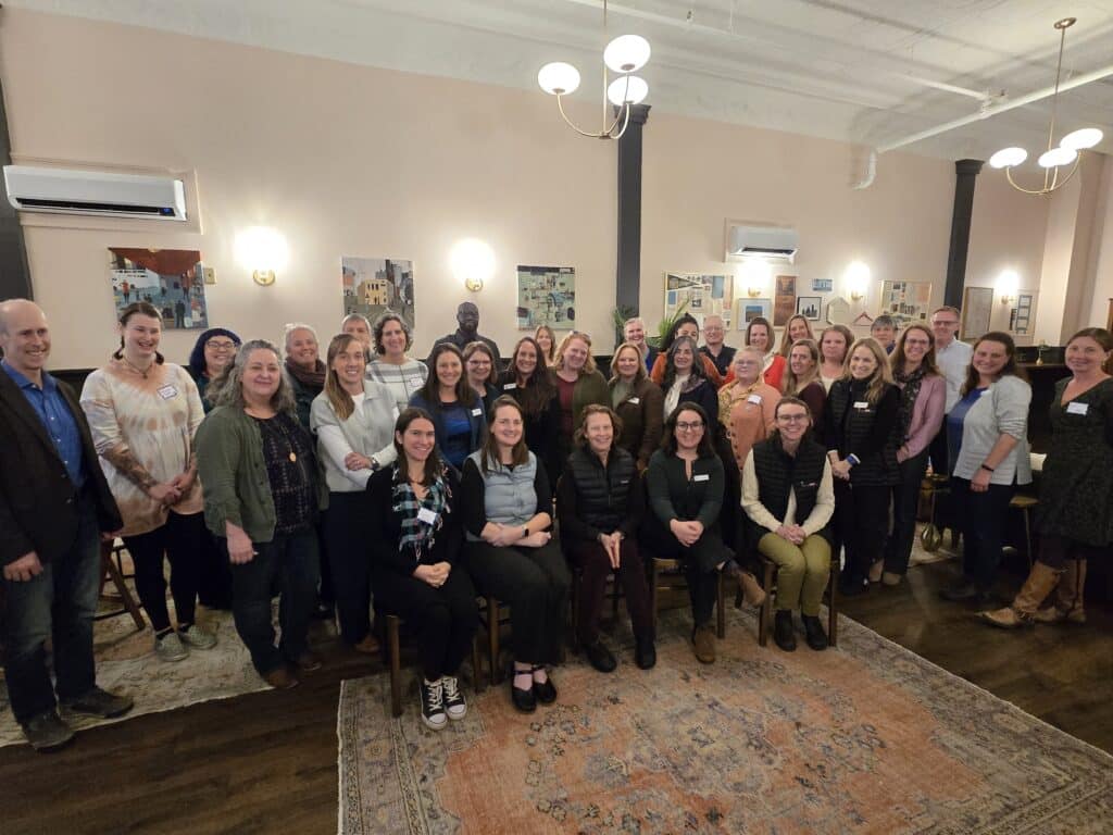 Members of the SAC and BBF staff standing and smiling with a faded antique rug in the foreground