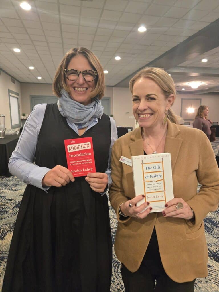 Two people smiling, one holding a book titled The Addiction Inoculation, the other holding a book titled The Gift of Failure