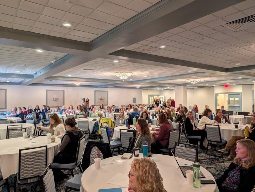 Many people seated at round tables in a conference room at the 2025 Regional Council Summit
