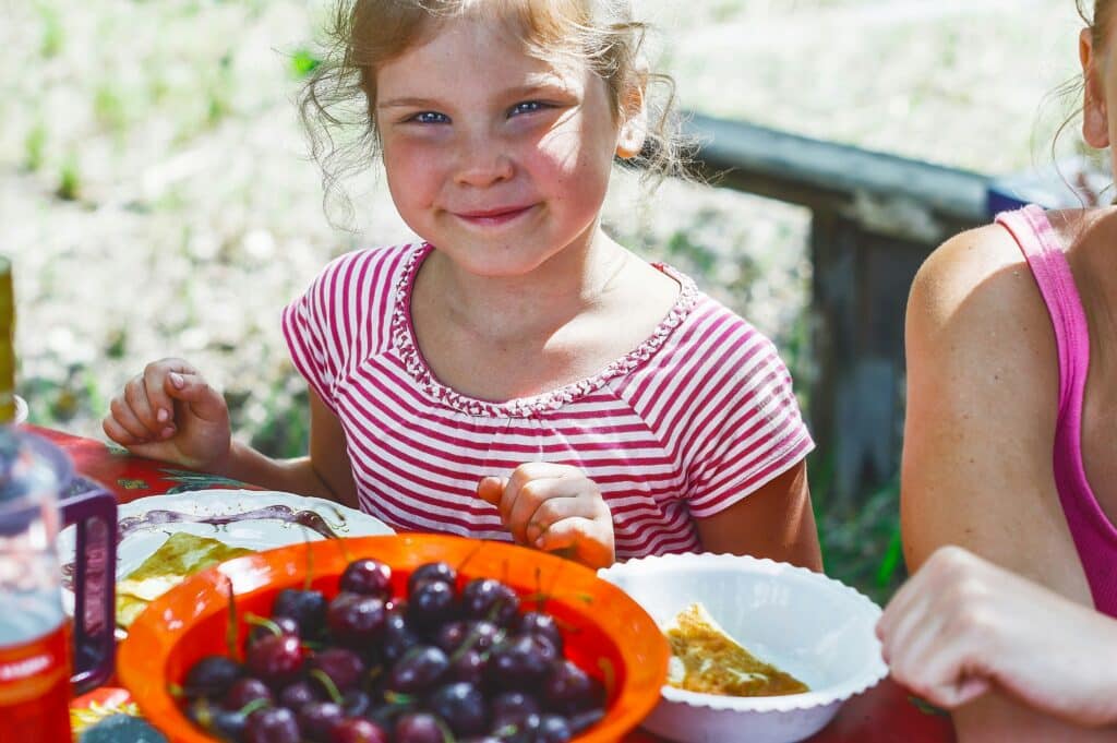 Smiling young child with bowl of cherries