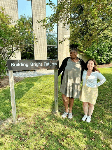 Titi and Anna standing next to the Building Bright Futures sign