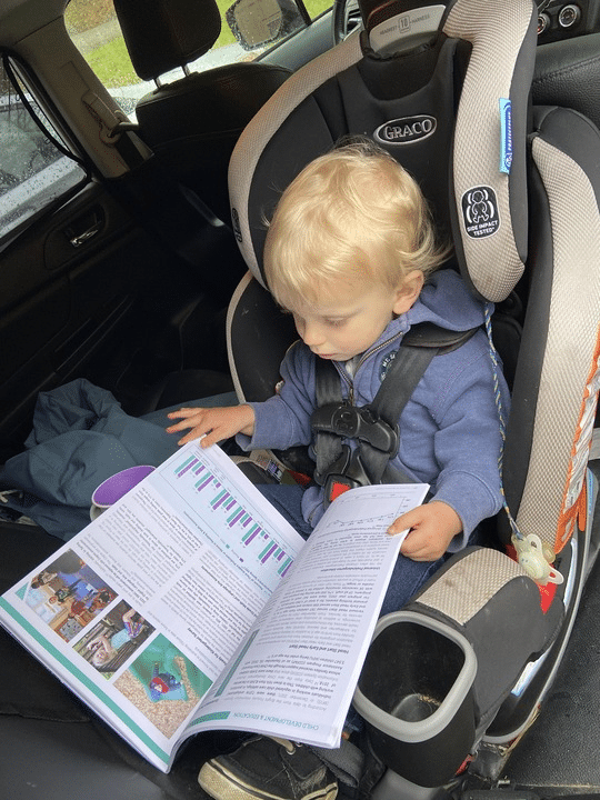 A young child in a car seat looking at a data brief