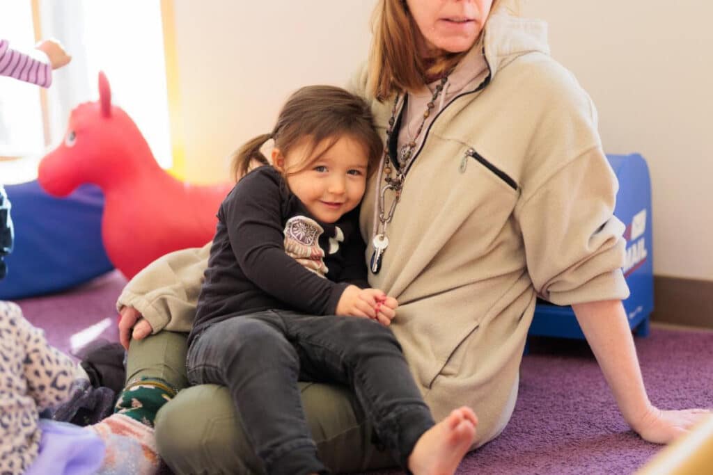 Young child sitting on parent's lap and smiling