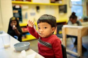 A young child eats food from a bowl