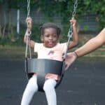 Young child being pushed on swing
