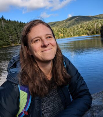 Jenn Schollmeyer smiling with a lake and mountains in the background
