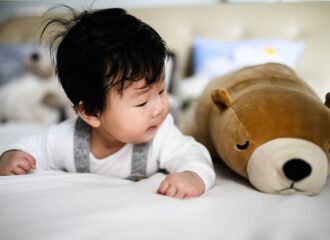 Infant on belly lifting head and looking at stuffed animal