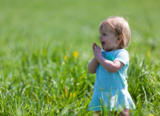Young child smiling in a field of green grass