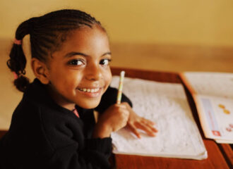 Young student smiling and holding a pencil